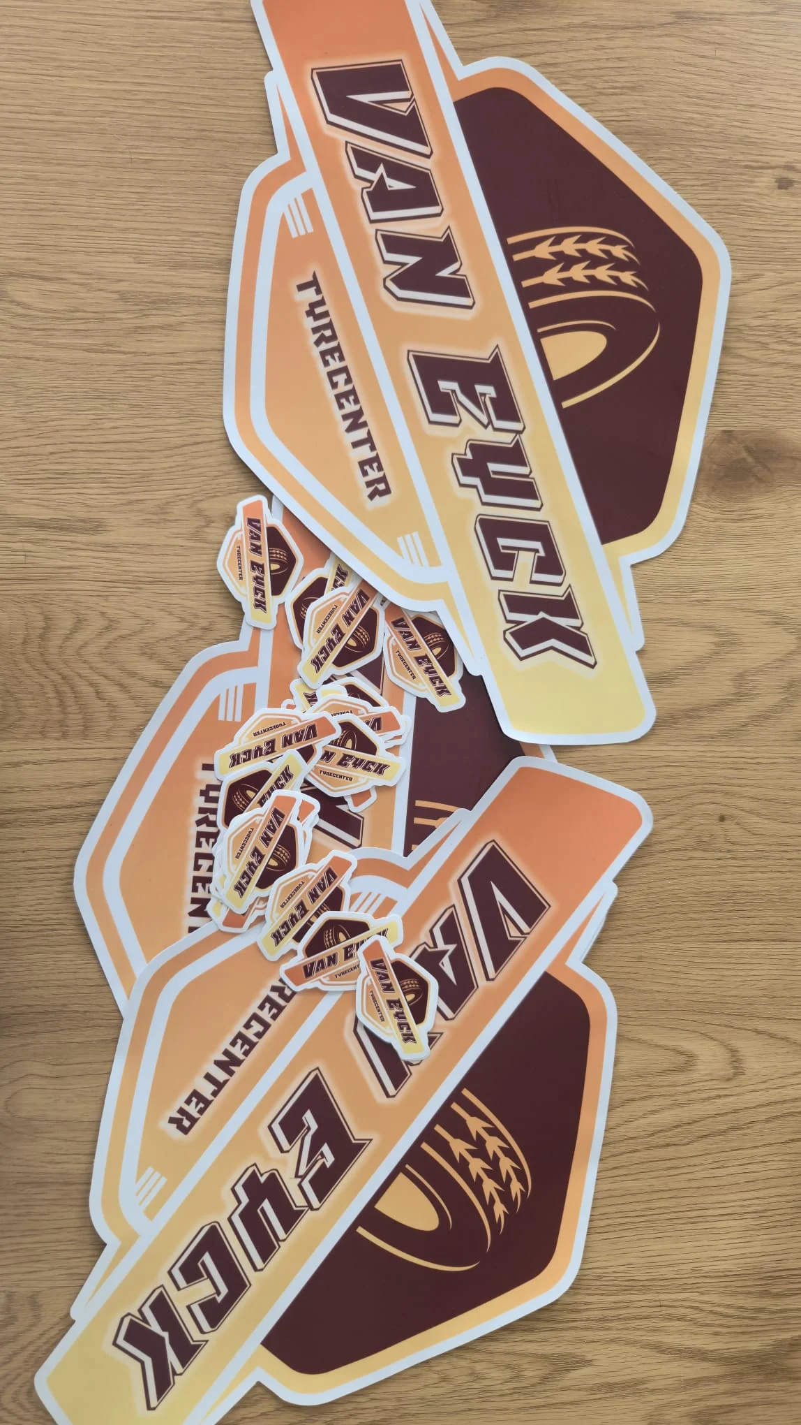 Grote en kleine Van Eyck Tyrecenter-stickers op een houten ondergrond